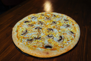 Italian pizza with mushrooms and cheese on a wooden table