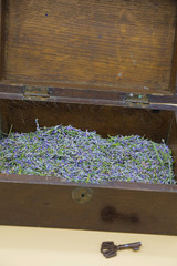 Brown vintage wooden chest with dried lavender flowers. The key near the chest. Copy space. Vertical image.