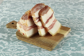 Sliced pork lard with meat streaks on a wooden cutting board