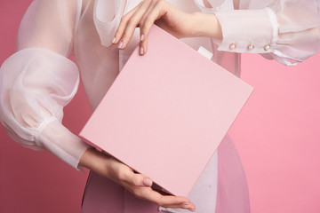  Close-up of a girl holding a pink box on a pink background