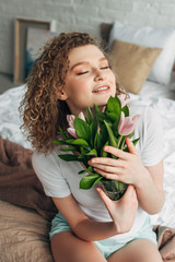 happy attractive girl in homewear holding tulip flowers in morning