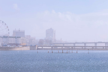 Obraz premium Cheboksary center and the water surface of the Bay in the spring of 2020 during a sudden snowstorm