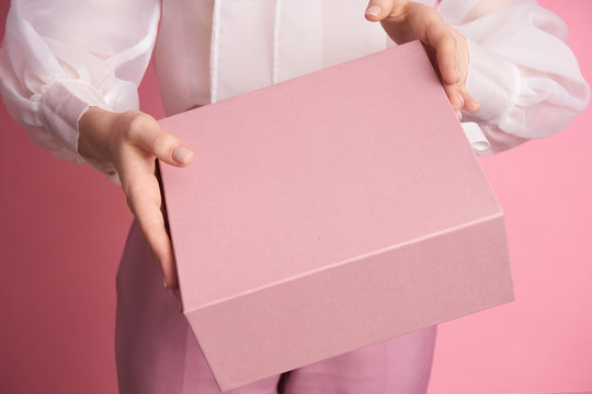  Close-up of a girl holding a pink box on a pink background