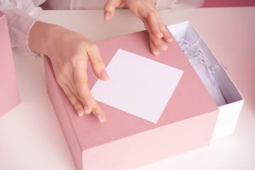 Female hands on a white table hold a box