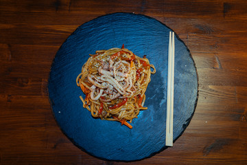 delicious Italian pasta spaghetti seafood vegetables and sesame on a black stone with Japanese sticks