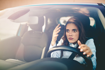 Road rage! Enraged young woman driver shouts and points accusingly.  Profile of an angry young driver. Negative human emotions face expression. Angry woman driving a car