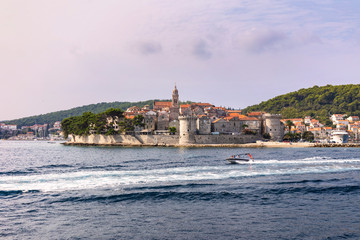 Naklejka premium Korcula island with the old city walls, view from the sea on a sunny day in the summer blue sky. Clear Adriatic sea, the south mediterranean coast of Croatia Europe. 