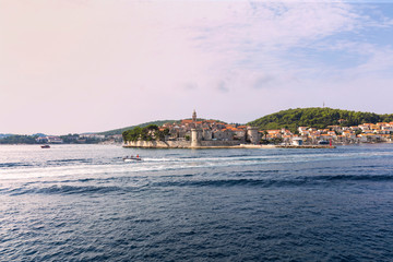 Obraz premium Korcula island with the old city walls, view from the sea on a sunny day in the summer blue sky. Clear adriactic sea, the south mediterranean coast of Croatia Europe. Beautiful landscape with greenery