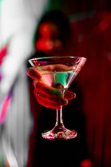 girl holds in her hand a beautiful red cocktail on the background of the bar