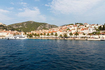 Fototapeta na wymiar Hvar town on Hvar island, view from the sea on a sunny day in the summer blue sky. Clear adriactic water, the south mediterranean coast of Croatia in Europe. Beautiful landscape with mountains