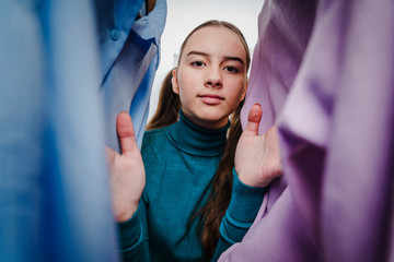 Teenage  Girl Looking Through Clothing Hangers.Teenage girl shopping for clothing - 346505234