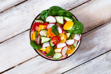 Concept of healthy food, clean eating, dieting. Colorful fresh vegetable salad in a bowl. Easy to cook, perfect summer light meal. Wooden background flat lay top view