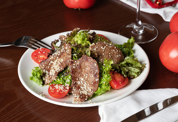 meat salad with veal on a white plate. Grilled meat with fresh vegetables