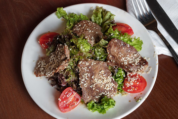 meat salad with veal on a white plate. Grilled meat with fresh vegetables