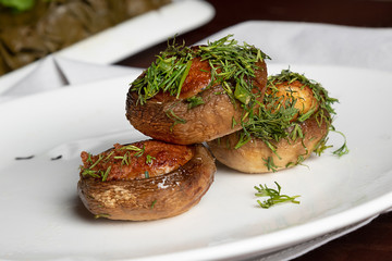 grilled mushrooms with cheese and  dill on white plate. Vegan food. Side view