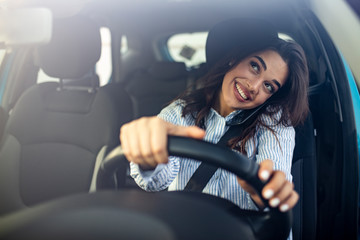 Businesswoman driving car and talking on cell phone concentrating on the road. Driver woman driving...
