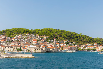 Pucisca town at Brac in Croatia, view from the sea on a sunny day in the summer. The port with it’s famous limestone from the island. Idyllic place, white stone creating a beautiful scenery