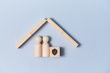 Family life and property insurance. Wooden figures family under house roof. Home building. Copy...