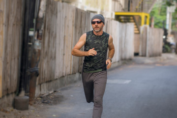 Fototapeta na wymiar outdoors urban jogging workout - young attractive and happy man running in the city enjoying fitness and sport in healthy lifestyle concept