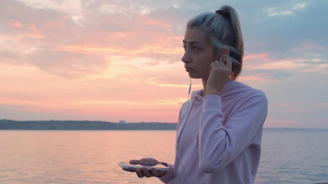 A young girl runs along the promenade, listening to music with headphones.