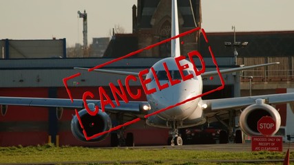 Air Travel Cancelled - A rubber stamp animation overlaid on a reversing airplane to illustrate the adverse effects of COVID-19 - Powered by Adobe