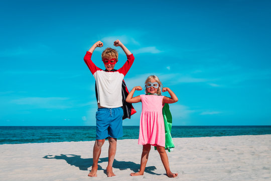 boy and girl play superheros on beach vacation
