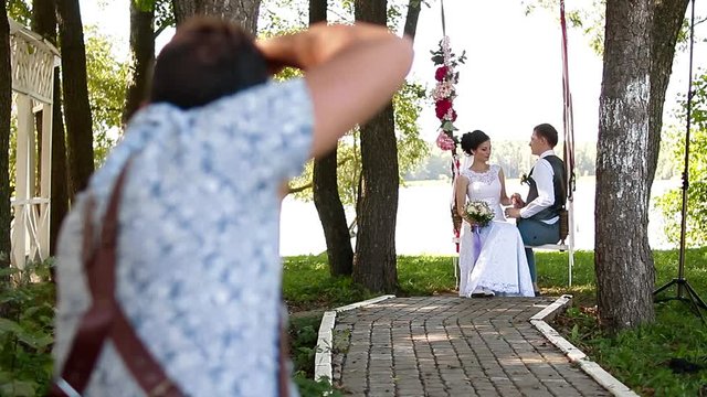 Wedding photographer taking pictures couple of newlyweds on a rope swing