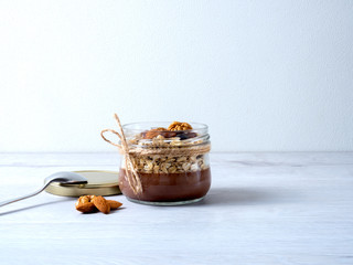 healthy breakfast of chocolate, oatmeal and nuts on a light wooden background