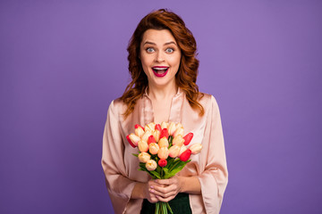 Photo of charming crazy lady hold bunch of fresh tulip flowers affectionate 8 march surprise party open mouth wear luxury beige shirt blouse isolated purple color background