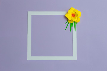 Square frame with yellow color paper flower on pastel violet blue background. Flat lay, copy space