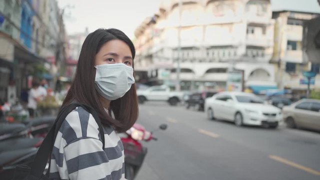 SLOW motion, Asian woman wear protective mask walking crossing street, during the day out, covid-19 corona, virus spreading prevention, Day time, new normal lifestyle, road side, Bangkok Thailand