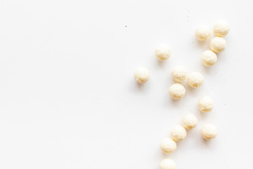 Coconut candy balls on white background top view copy space