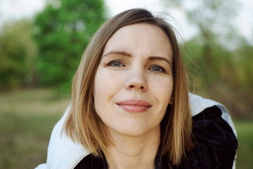 Middle-aged woman in a jacket on the street in the park.