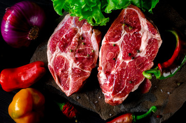 Two fresh raw ribeye steak on the stone on wooden background with salt, pepper