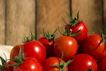 Small round cherry tomatoes with cuttings on a white napkin, wooden background. Delicious healthy vegetables, raw food.
