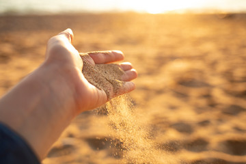 Close-up hand releasing dropping sand. Sand flowing through the hands.