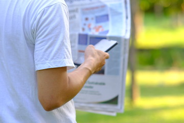 Man using smartphone in the park and checking social networks and reading business news