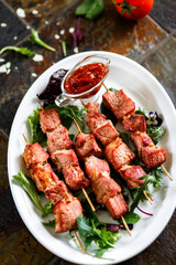Pork skewers with sauce and herbs on a wooden skewer