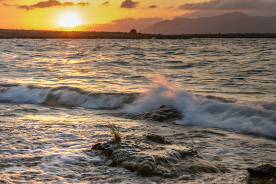 Wave striking stone on the sunset. Sevan lake, Armenia