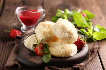 Healthy food. Sweetness in coconut shavings with strawberry jam in the bowl, fresh strawberries and mint on an old wooden background. Rustic. Background image, copy space