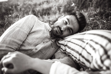 Portrait of a beautiful couple lying on the grass. Gently touch in the face, hug and kiss the girl. Hold hands