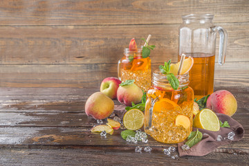 Fresh Homemade Peach Sweet Tea with Mint and Lemon Slices, Summer cold fruit drink. Wooden background with fresh peach, copy space