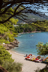 Bol beach on Brac island view with water cycles. With pebbles surrounded by pine trees, pines and greenery on a sunny day in summer in Dalmatia, Croatia. Clear blue Adriatic sea