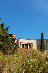 A Mediterranean house with light colored facades and a orange roof at bol, Brac island, Dalmatia, Croatia on a sunny day in summer with greenery and a blue sky. Serene idyllic scenery