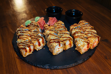 A set of sushi. Philadelphia roll, California, unagi, black dragon with fresh ingredients. The sushi menu. Japanese cuisine. Ginger and wasabi. Soy sauce. Sesame. Hot, baked, breaded