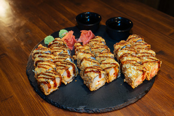A set of sushi. Philadelphia roll, California, unagi, black dragon with fresh ingredients. The sushi menu. Japanese cuisine. Ginger and wasabi. Soy sauce. Sesame. Hot, baked, breaded