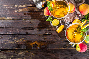 Refreshing summer drink, peach martini cocktails with gin or vodka and fresh peach garnish, wooden background copy space