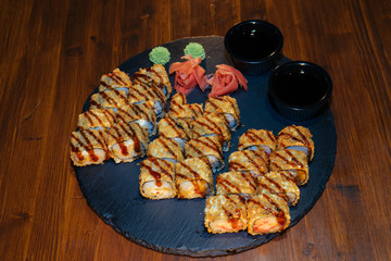 A set of sushi. Philadelphia roll, California, unagi, black dragon with fresh ingredients. The sushi menu. Japanese cuisine. Ginger and wasabi. Soy sauce. Sesame. Hot, baked, breaded
