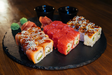 A set of sushi. Philadelphia roll, California, unagi, black dragon with fresh ingredients. The sushi menu. Japanese cuisine. Ginger and wasabi. Soy sauce. Sesame. Hot, baked, breaded