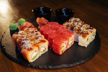 A set of sushi. Philadelphia roll, California, unagi, black dragon with fresh ingredients. The sushi menu. Japanese cuisine. Ginger and wasabi. Soy sauce. Sesame. Hot, baked, breaded